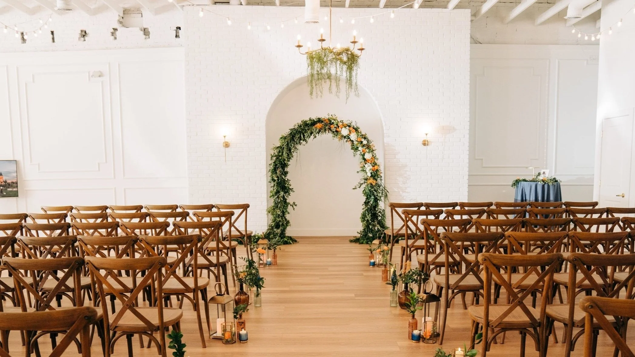 Amavi Event Venue - Elegant white brick interior with floral arch and string lights